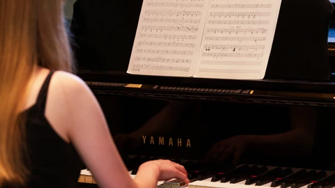 Ein Mädchen sitzt am Klavier und übt konzentriert ihr Musikstück.