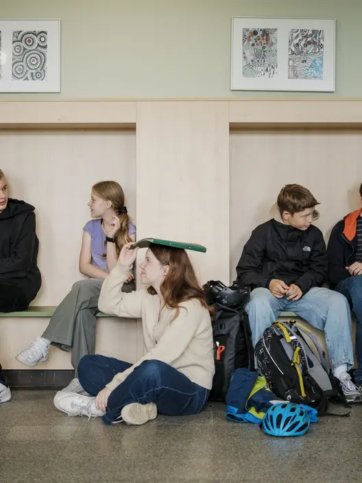 Schüler sitzen auf dem Schulflur