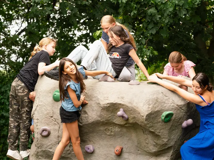Sechs Mädchen klettern in der Natur und haben Spaß.