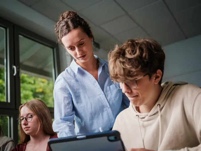 Lehrerin in einem Klassenraum. Infobox mit drei Stichpunkten zu den Vorteilen der Oberstufe am Gymnasium Elze.